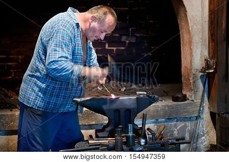 Ruzomberok Slovakia - June 30 2012: Blacksmith working metal on the anvil in the forge. Metal products handmade in the workshop