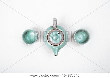 Green teapot with cups on white background.