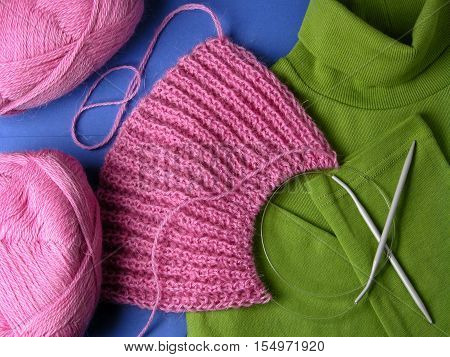 Knitten things isolated on blue with a knitting needles.
