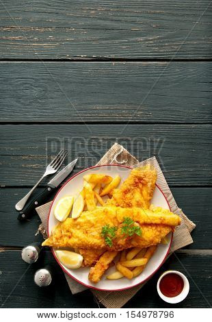 Two pieces of battered fish on a plate with chips