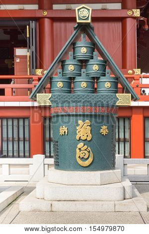 Tokyo Japan - September 26 2016: In front of vermilion Honzo main hall of the Senso-ji Buddhist Temple stands a sculpture depicting water pit and stack of buckets all painted dark green. Gold details.