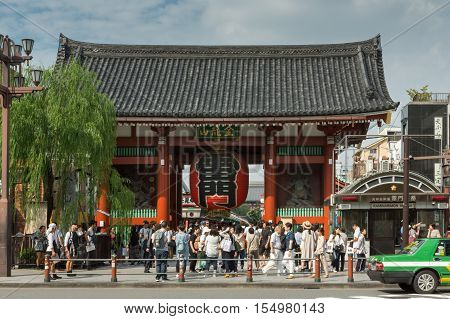 Tokyo Japan - September 26 2016: The vermilion painted Kaminarimon gate of Senso-ji Buddhist Temple stands close to the main road and is the gate most visitors pass through. Lots of people. Blue cloudy sky.