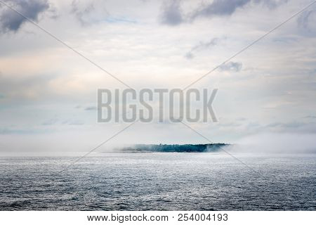 Beautiful Nordic Archipelago Summer View  Of A Island Surrounded By Thick Haze And Fog At The Horizo
