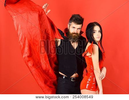 Attractive Demon Concept. Couple On Strict Face Play Role Game. Vampire In Cloak And Sexy Devil Girl