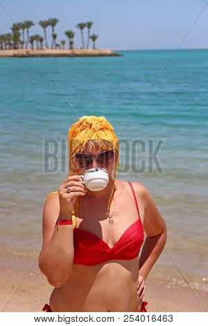Girl Drinking Coffee Standing On Beach During Vacation. Woman Enjoying Holidays