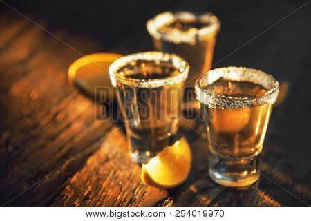 Three Glasses Of Tequila And Lime On A Dark Background In The Bar