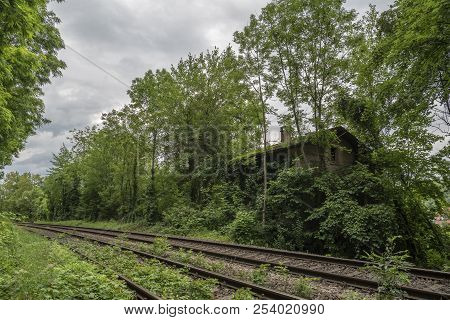 House Left Alone In The Forest, Near A Railway, Overtaken By Nature, Covered With Vegetation
