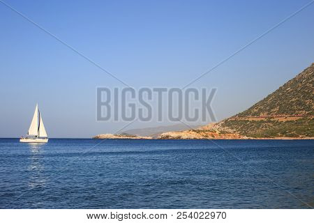 White Sailboat In The Open Mediterranean Sea On A Sunny Day. Sailing Yacht In The Open Sea With Moun