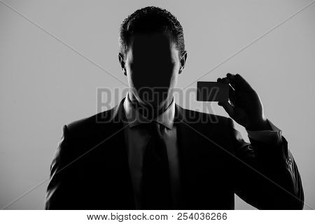 Faceless Man In Formal Suit And Tie On Grey Background. Shadow Business And Economy, Banking, Fraud,