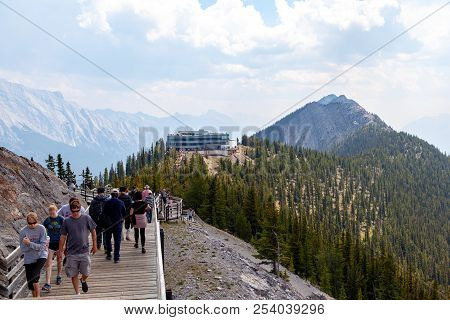 Banff, Canada - Aug 1, 2018: Visitors Walk The Wooden Boardwalk On Top Of Sulphur Mountain Between T