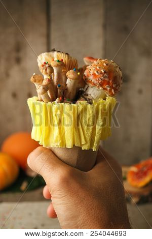 Fantastic Ice Cream With Candy Mashroom In Hand On Wooden Background, Concept Of Poisin, Nagic Food,