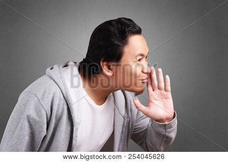 Young Asian Man Wearing Jacket Whispering And Gossiping