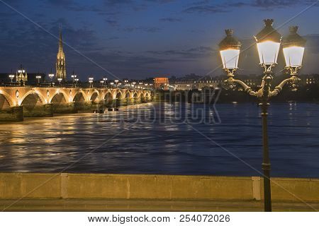 Pont De Pierre Stone Bridge On The River Garonne In Bordeaux, France At Sunset With The St Michel Ch
