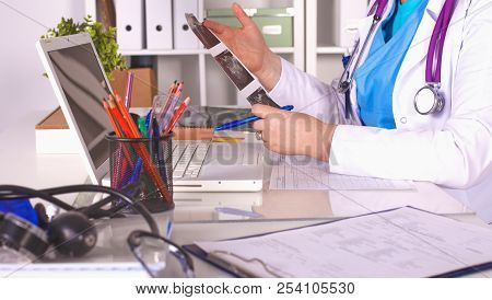 Medical Doctor  Sitting At Table And Looking Patients Roentgen