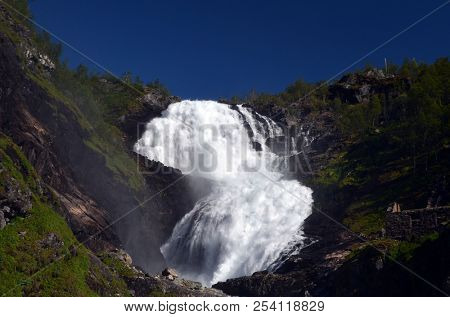 Kjosfossen waterfall flows down valley by the station on the train between Flam and Myrdal in Norway