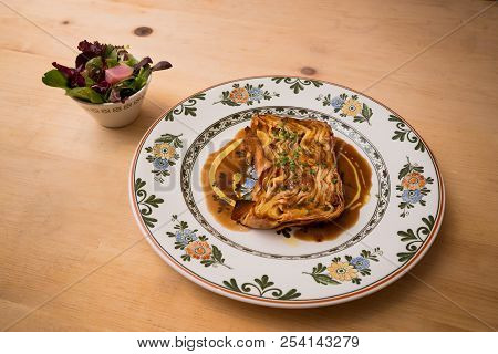 A Plate Of Timballo Pasta With A Side Salad.