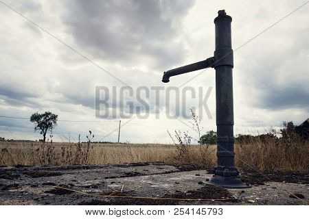 Old Pump With Dry Soil, Dramatic Cloudy Sky, Water Shortage