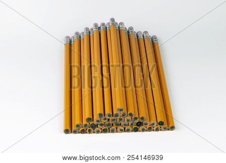 A Stack Or Orange, Unsharpened, Six-sided Pencils Neatly Stacked In A Pyramid With The Pink Erasers 