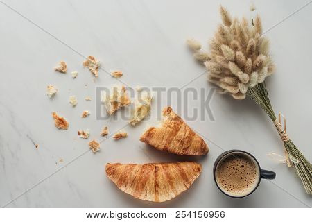 Top View Of Cup Of Delicious Coffee With Croissants And Bouquet Of Bunnytail Ears On White Marble