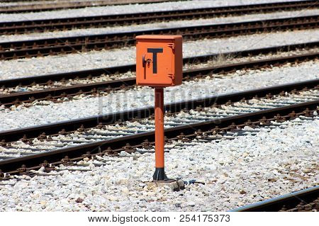 Railway Trackside Orange Communication Utility Box With Lock And Key Mounted On Metal Pole And Posit