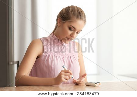 Diabetic woman taking blood sample with lancet pen at home