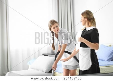 Chambermaid in uniform teaching trainee indoors