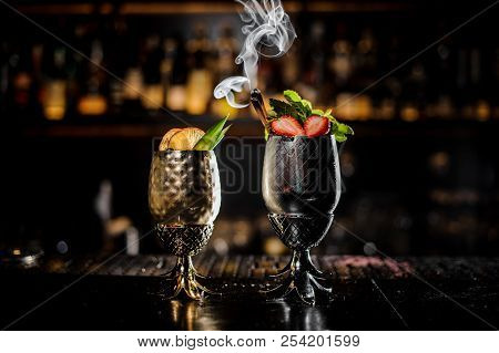 Two Metal Glasses Of Fresh Summer Cocktails Decorated With Fruit And Fume On The Bar Counter