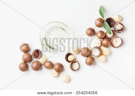 Cosmetic Macadamia Oil And Heap Of Nuts On White Table Top View.