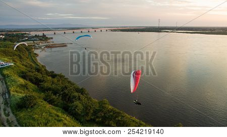 Silhouette Flying Paramotor Over River And Sunset Sky