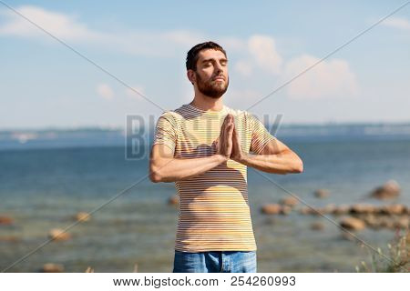 meditation, spirituality and mindfulness concept - man meditating outdoors over sea