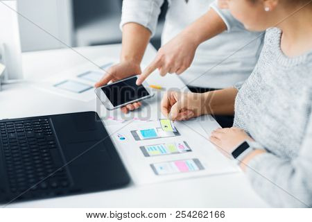 app design, technology and business concept - web designers or developers with smartphone working on user interface at office