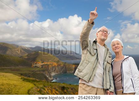 old age, tourism, travel and people concept - happy senior couple over bixby creek bridge on big sur coast of california background