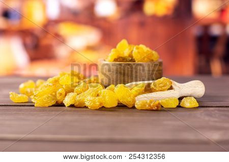 Lot Of Whole Dry Golden Raisins Sultana Variety Scoop With Wooden Bowl With Rustic Wood Kitchen In B