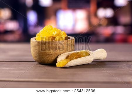Lot Of Whole Dry Golden Raisins Sultana Variety Scoop With Wooden Bowl With Restaurant In Background
