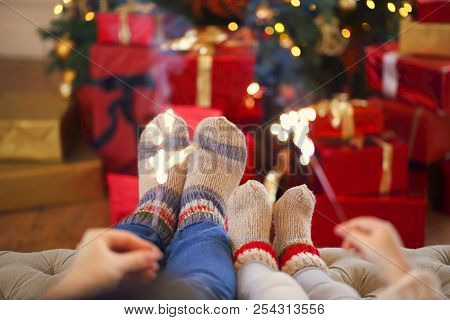 Happy Family With Bengal Lights Over The Christmas Background. Mother And Daughter By The Christmas 