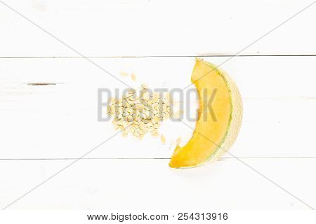 One Slice Of Fresh Melon Cantaloupe Variety With Seeds Around Flatlay On Grey Wood
