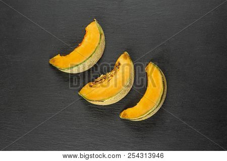 Group Of Three Slices Of Fresh Melon Cantaloupe Variety Flatlay On Grey Stone