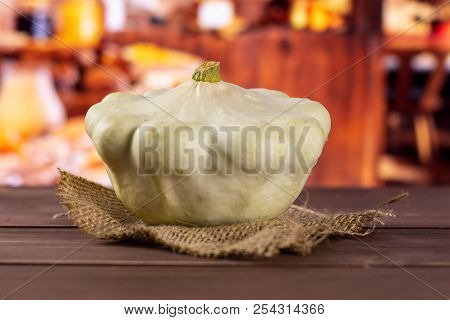 One Whole Summer White Pattypan Squash On Linen Cloth With Rustic Wood Kitchen In Background