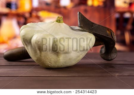One Whole Summer White Pattypan Squash With A Hammer With Rustic Wood Kitchen In Background