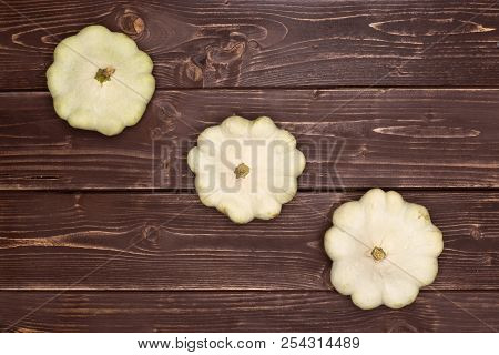 Group Of Three Whole Summer White Pattypan Squash In Line Flatlay On Brown Wood