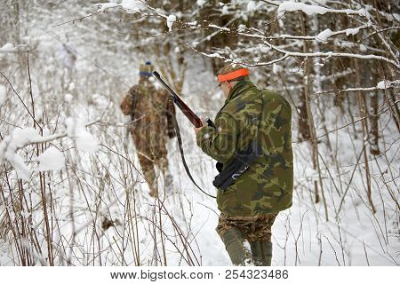 Group Of Hunters In Winter Forest With Carbines And Shotgun