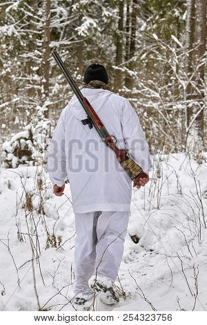 Hunter In Winter Camouflage With Shotgun In The Forest