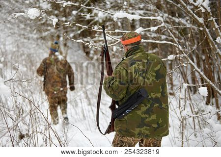 Group Of Hunters In Winter Forest With Carbines And Shotgun