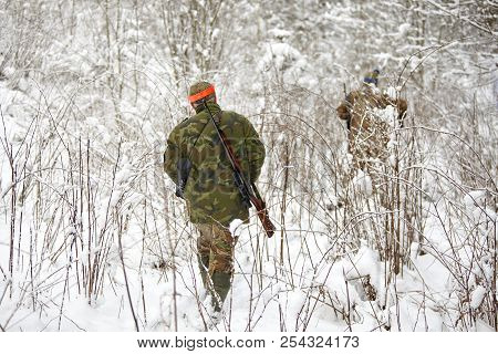 Group Of Hunters In Winter Forest With Carbines And Shotgun