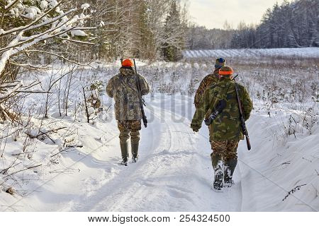 Group Of Hunters In Winter Forest With Carbines And Shotgun