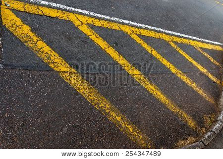 A Yellow Pianted Island On The Coner Of A Main Road To Show No Parking