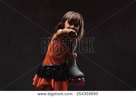 Little Girl Dressed In Skater Dress Holds Ice Skates Scoffs And Points With His Finger. Isolated On 