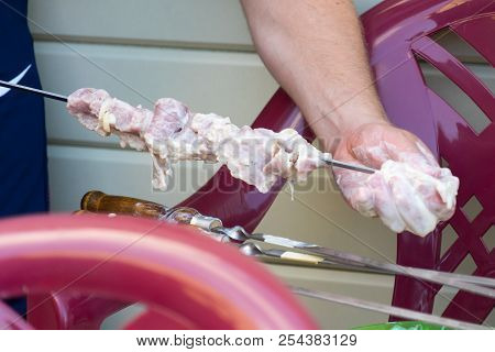 The Man Stringing The Meat For Subsequent Cooking On The Fire.