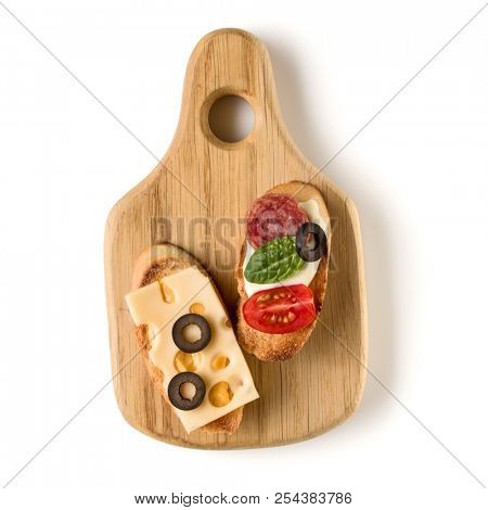 Open faced sandwich canape or crostini on a wooden serving board isolated on white background closeup. Top view.