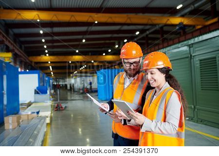Waist Up Portrait Of Smiling Female Factory Worker Using Digital Tablet While Discussing Production 
